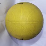 Yellow basketball with textured surface and traditional panel lines, placed on a white background.