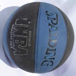 Black and blue NBA Spalding Basketball with textured grip and official branding, placed on a white surface.