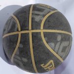 Black Spalding Basketball with yellow branding and textured grip, placed on a white surface.