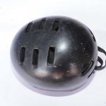 Black sports helmet with ventilation slots and adjustable strap, designed for impact protection and comfort.