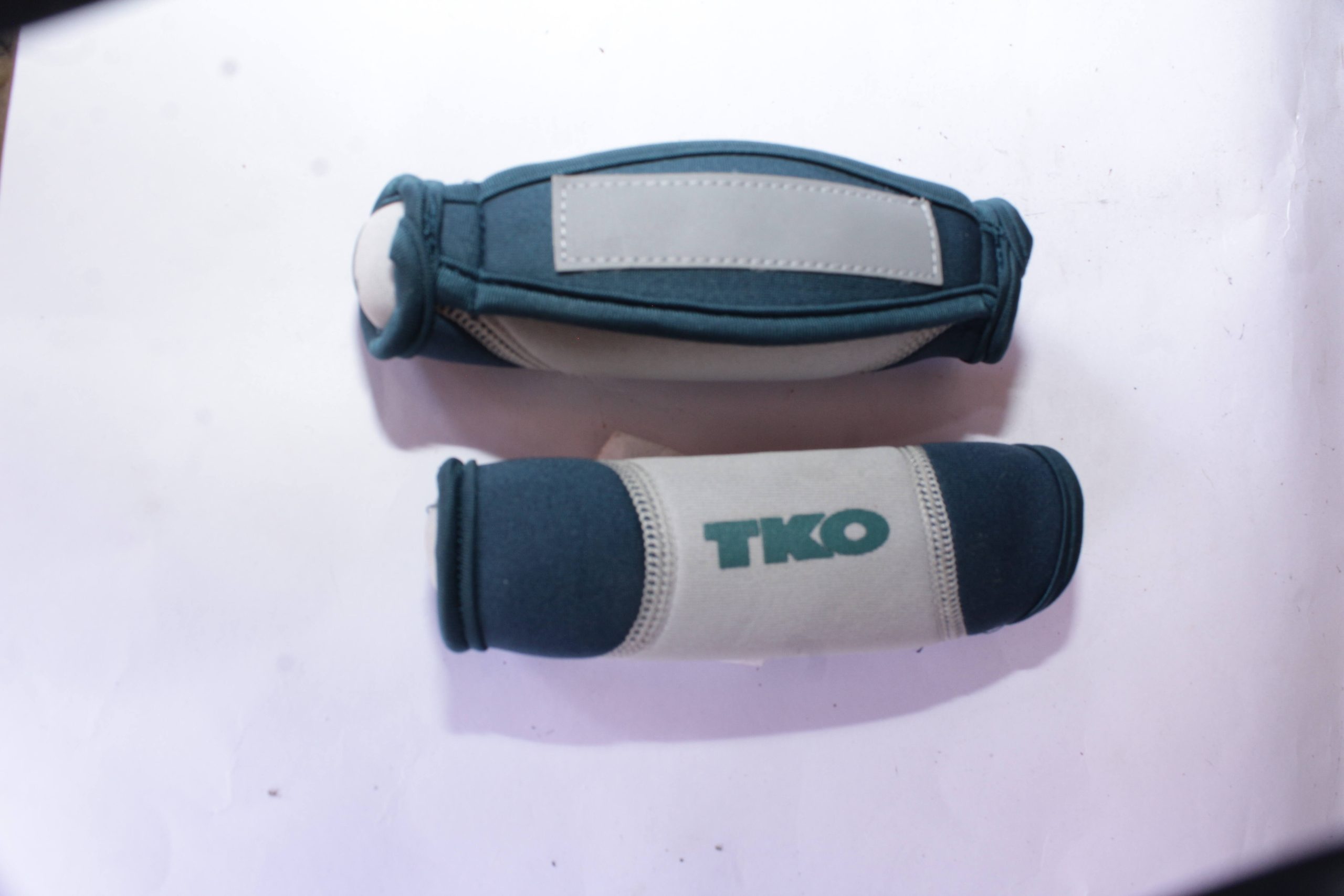 Pair of TKO wrist/ankle weights covered in blue and gray fabric with a secure adjustable fit, placed on a white surface.
