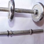 Two metal dumbbells—one fully assembled with weight plates, one without plates—featuring textured grips and threaded locking ends, displayed on a white surface.