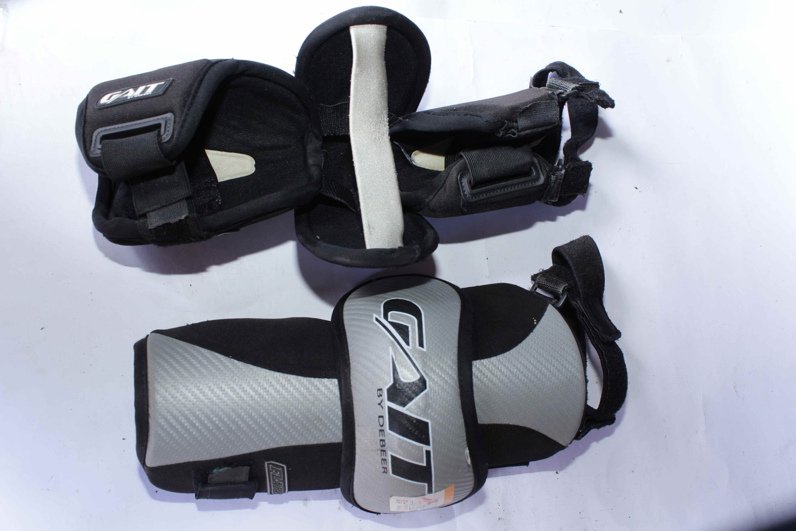 A pair of GAIT by DEBEER Elbow Pads with durable padding and adjustable straps, designed for impact protection in contact sports like lacrosse and hockey.
