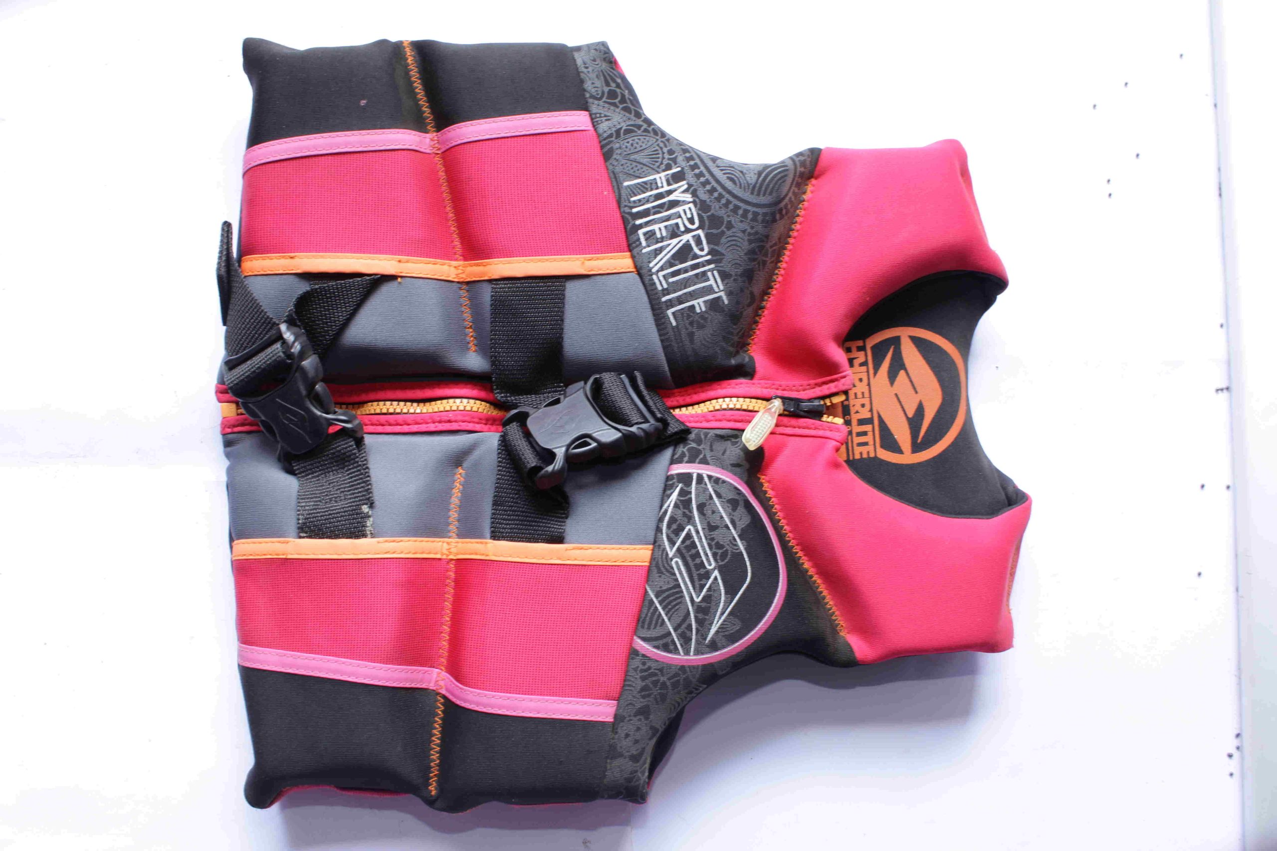 Hyperlite Life Jacket with black, pink, gray, and orange panels, featuring two black adjustable straps with buckles, front zipper with gold pull, and brand logo, displayed on a white surface.