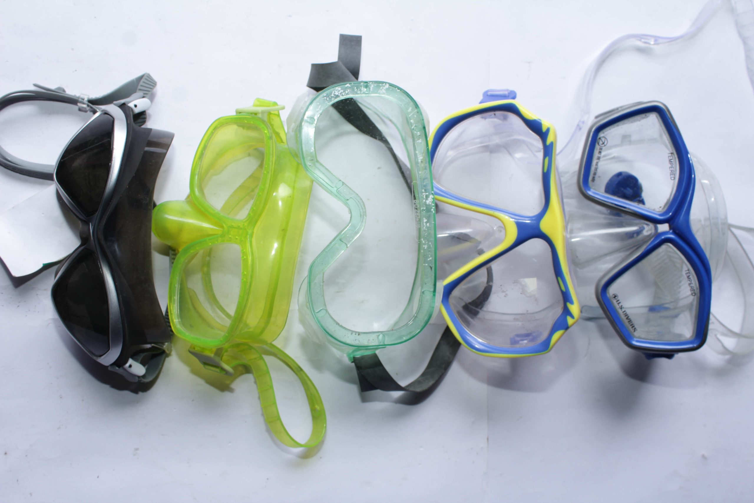 Five pairs of swimming and diving goggles with varied tinted and clear lenses, designed for underwater clarity and secure fit.