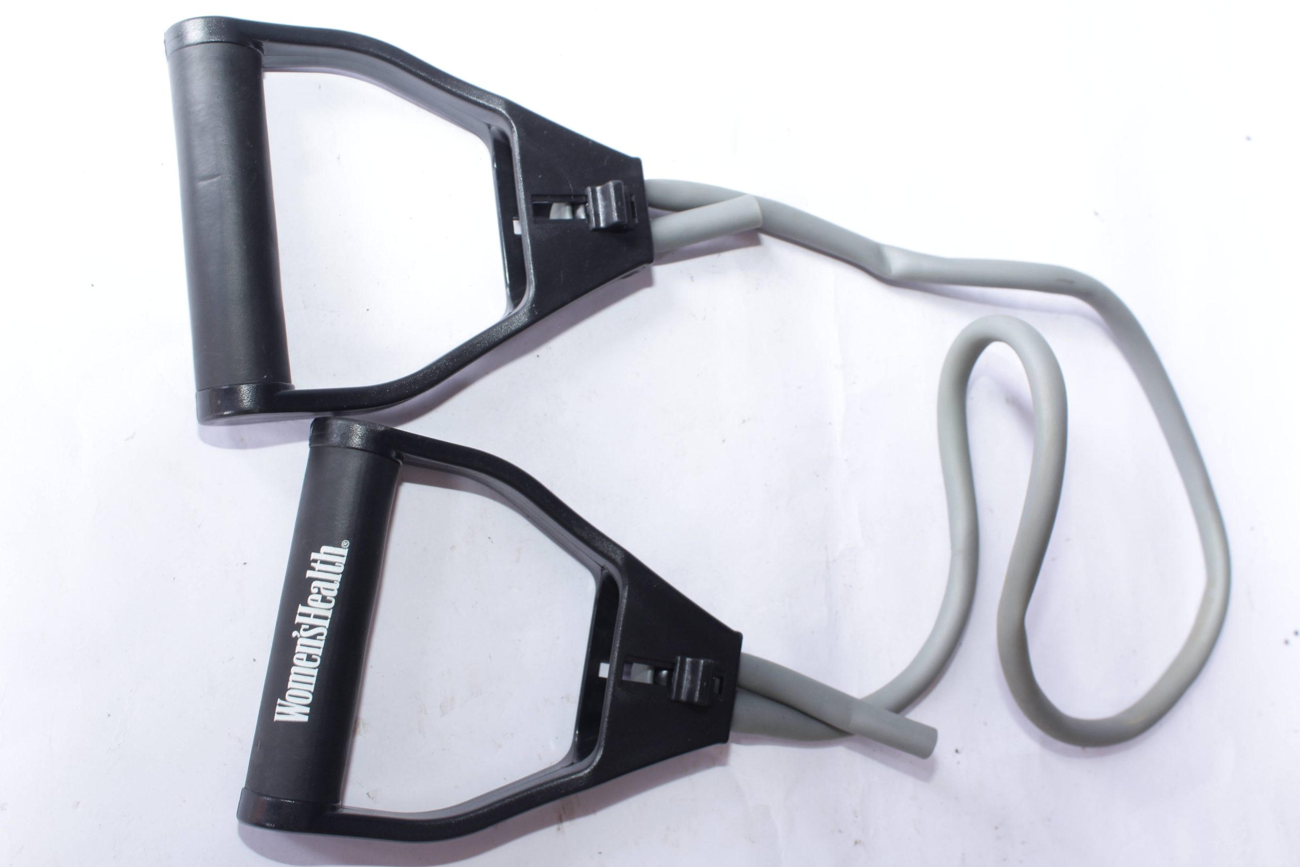 Women's Health resistance band exercise equipment with black handles and grey elastic band, designed for versatile home fitness workouts.