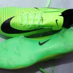 Bright green Nike ACC soccer cleats with black branding, textured grip, and translucent studded sole for firm-ground traction, displayed on a white surface.
